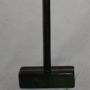 May include: A dark green croquet mallet with a black handle and grip. The mallet head is rectangular with a thin gold stripe. The handle is 86 cm long.