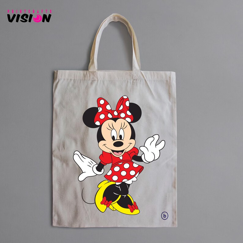 May include: A white canvas tote bag with a red and white polka dot Minnie Mouse design. The bag has black handles and a red bow on Minnie's head.