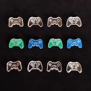May include: Twelve small plastic game controllers in three colors: clear, green, and blue. The controllers are all the same size and shape, and they have a white outline.
