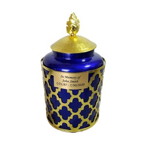 May include: A blue and gold urn with a gold leaf design on the lid. The urn has a personalised inscription that reads "In Memory of John Smith 1/21/87 - 7/30/2020".