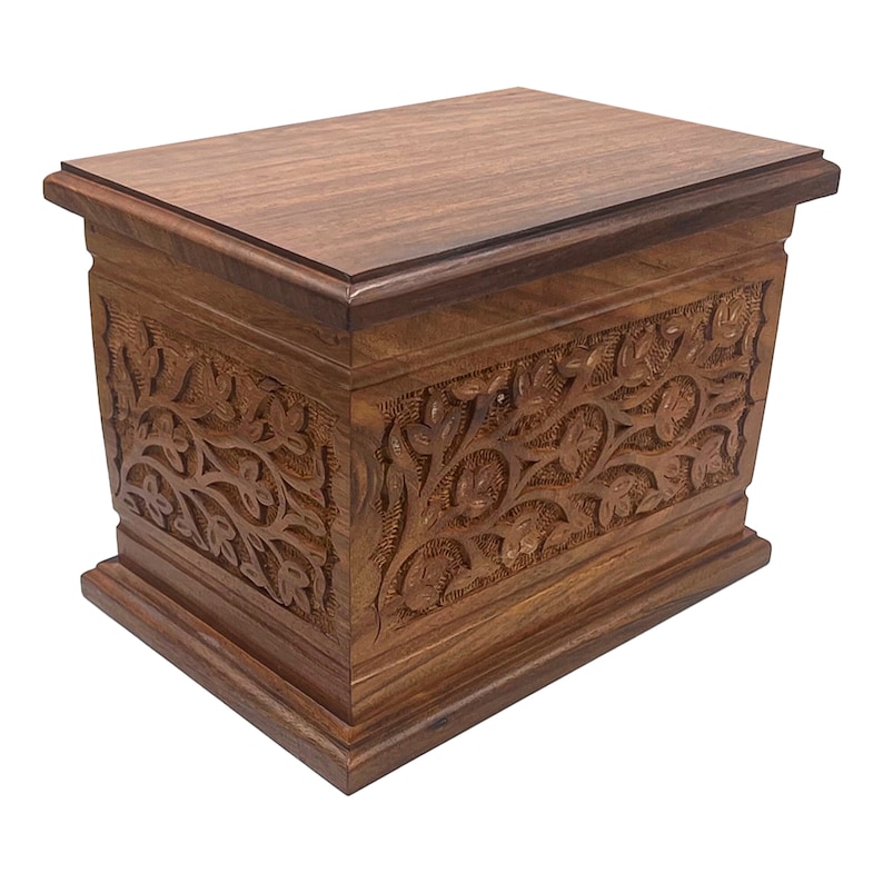 May include: A wooden box with intricate floral carvings. The box is made of dark brown wood and has a hinged lid. The carvings are detailed and cover the entire surface of the box.