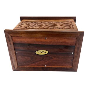May include: A wooden box with intricate carvings on the top and a gold label on the front that reads "NWA".