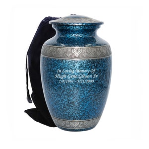 May include: A blue and silver metal cremation urn with a personalized inscription. The urn has a speckled blue finish and silver trim. It comes with a black velvet bag.