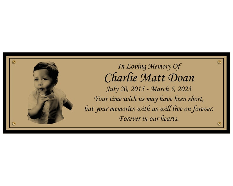 May include: A gold memorial plaque with a black border and a photo of a young boy. The plaque reads "In Loving Memory Of Charlie Matt Doan July 20, 2015 - March 5, 2023 Your time with us may have been short, but your memories with us will live on forever. Forever in our hearts."