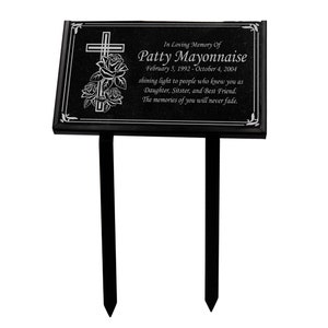 Może przedstawiać: Czarna tablica pamiątkowa z krzyżem i różami. Na tablicy napisano "In Loving Memory Of Patty Mayonnaise" z datami i krótką wiadomością. Dwa czarne kołki do umieszczenia w ziemi.