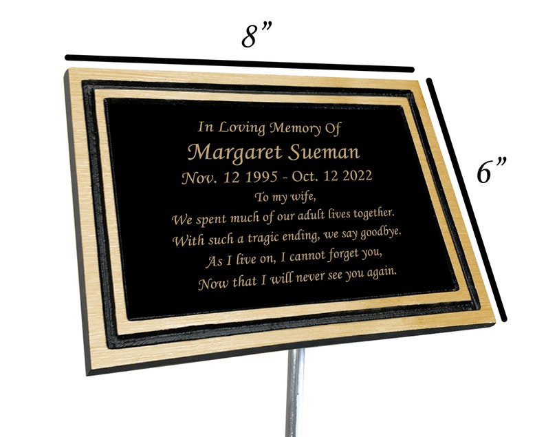 May include: A black and gold memorial plaque with a personalized message for Margaret Sueman. The plaque is 8 inches wide and 6 inches tall. It reads "In Loving Memory Of Margaret Sueman Nov. 12 1995 - Oct. 12 2022 To my wife, We spent much of our adult lives together. With such a tragic ending, we say goodbye. As I live on, I cannot forget you, Now that I will never see you again."