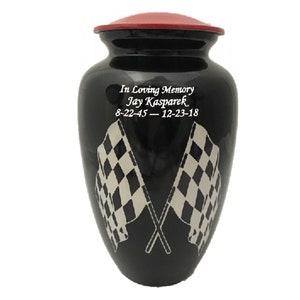 May include: Black cremation urn with a red lid, featuring two crossed chequered flags and the inscription "In Loving Memory Jay Kasparek 8-22-45 - 12-23-18"