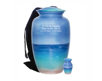 May include: A blue and white cremation urn with a beach scene and the inscription "In Loving Memory Tina Marie Harris 11/12/1965 - 1/17/2022". The urn is accompanied by a smaller matching urn.