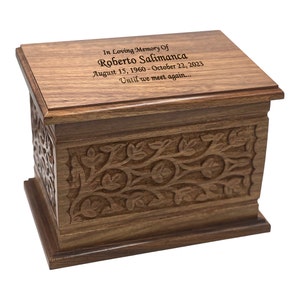 May include: A wooden cremation urn with an intricate carved floral design. The lid has an inscription that reads "In Loving Memory Of Roberto Salimanca August 15, 1960 - October 22, 2023 Until we meet again..."