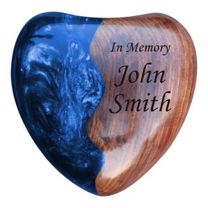 Może przedstawiać: Drewniana skrzynka na pamiątki w kształcie serca z niebieską wkładką z żywicy. Skrzynka jest grawerowana słowami "In Memory John Smith".
