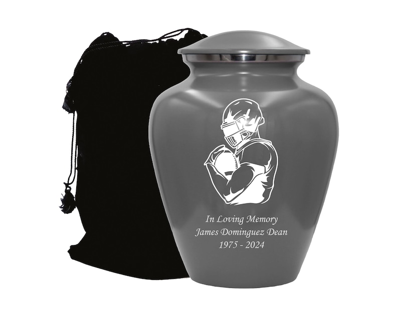 May include: Gray metal urn with a white silhouette of a football player holding a football. The urn has the text "In Loving Memory James Dominguez Dean 1975 - 2024" engraved on the front.