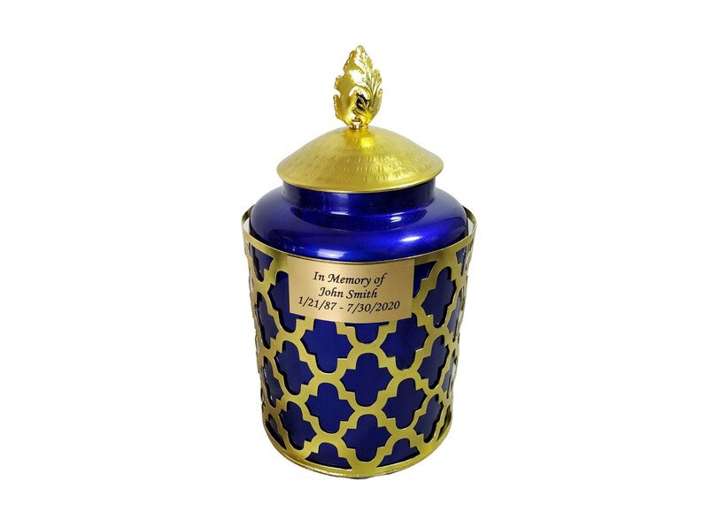 May include: A blue and gold urn with a gold leaf design on the lid. The urn has a personalised inscription that reads "In Memory of John Smith 1/21/87 - 7/30/2020".