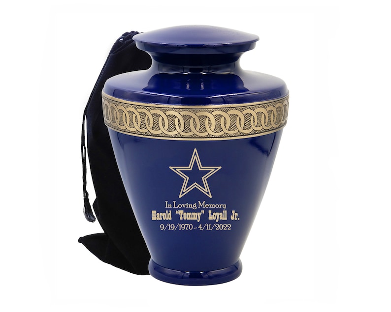 May include: A blue and gold metal urn with a star design and the inscription "In Loving Memory Harold "Tommy" Loyall Jr. 9/19/1970-4/11/2022".
