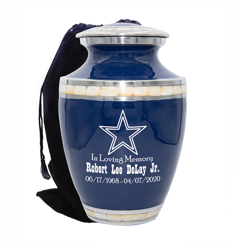 May include: A blue and silver cremation urn with a white star and the inscription "In Loving Memory Robert Lee DeLay Jr. 06/17/1968-04/07/2020".
