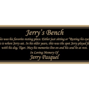 May include: A black plaque with gold lettering that reads "Jerry's Bench". The plaque has a gold border and is mounted on a wall. The text on the plaque reads: "This was his favorite resting place. Either just sitting or "Resting his eyes." This is where Jerry sat. In his older years, this was the spot Jerry played fetch with his dog, Tiger. May his memories live on and his soul be at rest. In Loving Memory Of Jerry Pasquel"