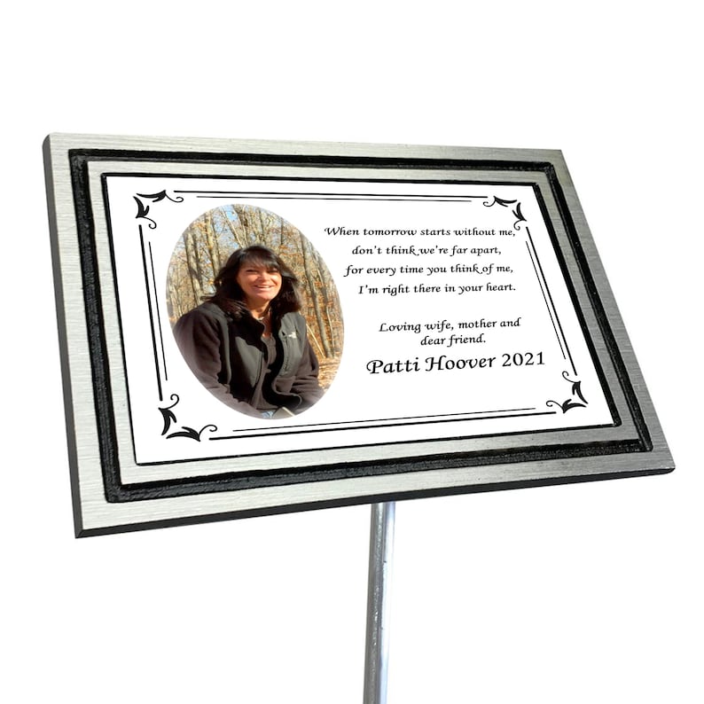 Puede incluir: Una placa conmemorativa de metal plateado con borde negro y una foto de una mujer en un bosque. La placa tiene un poema sobre recordar a alguien que ha fallecido y el texto "Loving wife, mother and dear friend. Patti Hoover 2021".