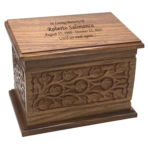 May include: A wooden cremation urn with an intricate carved floral design. The lid has an inscription that reads "In Loving Memory Of Roberto Salimanca August 15, 1960 - October 22, 2023 Until we meet again..."