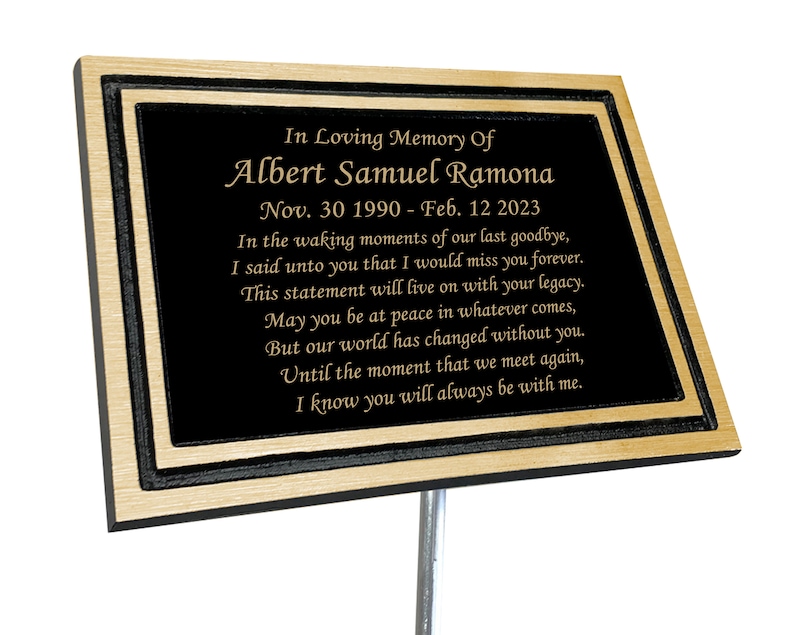May include: A black granite memorial plaque with gold lettering. The plaque reads "In Loving Memory Of Albert Samuel Ramona Nov. 30 1990 - Feb. 12 2023" and includes a poem about remembering a loved one.