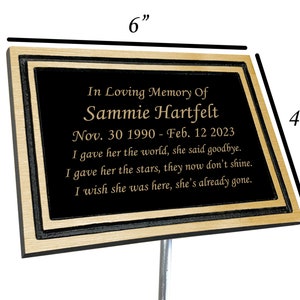 May include: A 6-inch by 4-inch black memorial plaque with gold trim and lettering. The plaque reads "In Loving Memory Of Sammie Hartfelt Nov. 30 1990 - Feb. 12 2023 I gave her the world, she said goodbye. I gave her the stars, they now don't shine. I wish she was here, she's already gone."