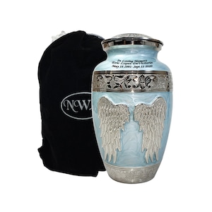 May include: A light blue cremation urn with silver-colored accents and angel wings design. The urn has the inscription "In Loving Memory Eric Lopez DeVictoria May 16 1991- Sept 11 2020". A black velvet bag with a white logo is on the left.