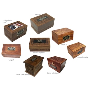 May include: A selection of wooden cremation urns in different sizes and styles. The urns are intricately carved and have a polished finish. Some urns have a latch, while others have a photo insert.