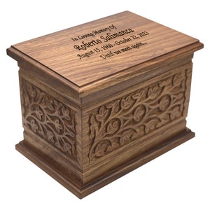 May include: A wooden cremation urn with an intricate floral carving design. The lid has an inscription that reads "In Loving Memory Of Roberto Salimanca August 15, 1960 - October 22, 2023 Until we meet again..."