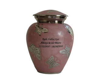 May include: A pink urn with silver butterfly accents and a silver lid. The urn has the inscription "Ruth Valloa Keir Always in our Hearts 15/12/1937 - 18/10/2010". The urn is a memorial item.