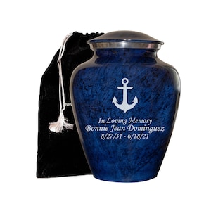 May include: Blue cremation urn with a silver lid and an engraved anchor. The urn has the text "In Loving Memory Bonnie Jean Dominguez 8/27/31 - 6/18/21" engraved on the front.