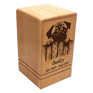 May include: A wooden pet urn with a laser engraved image of a pug peeking over a fence. The urn is inscribed with the name "Bailey" and the dates "Jan 2010 - June 2023".