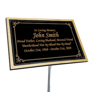 May include: Black memorial plaque with gold lettering. The plaque reads "In Loving Memory John Smith Proud Father, Loving Husband, Devoted Friend "Brotherhood Not By Blood But By Bond" October 21st, 1968 - October 31st, 2020"