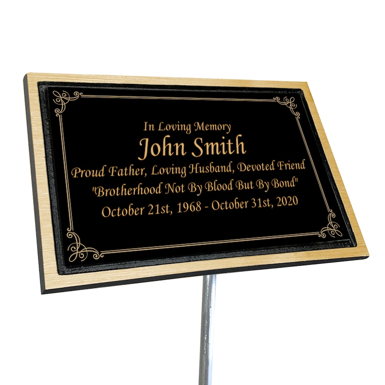 May include: Black memorial plaque with gold lettering. The plaque reads "In Loving Memory John Smith Proud Father, Loving Husband, Devoted Friend "Brotherhood Not By Blood But By Bond" October 21st, 1968 - October 31st, 2020"