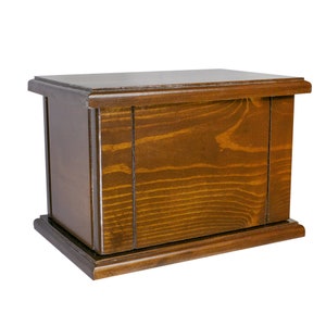 May include: A dark brown wooden box with a simple design. The box has a smooth, polished finish and a slightly raised base.