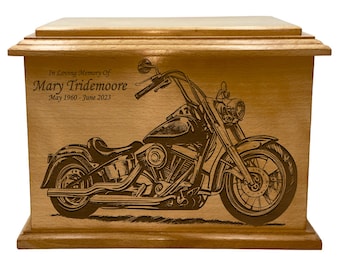 Könnte beinhalten: Hellbraune Holzurne mit eingraviertem Motorrad-Design. Der Text "In Loving Memory Of Mary Tridemoore May 1960 - June 2023" befindet sich über dem Motorradbild. Die Urne ist rechteckig mit flachem Deckel.