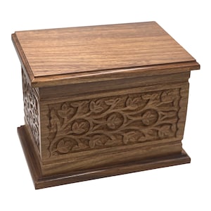 May include: A wooden box with intricate floral carvings on the front and sides. The box is made of dark brown wood and has a smooth, polished finish.