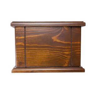 May include: A dark brown wooden box with a simple design. The box has a smooth, polished finish and a rectangular shape.