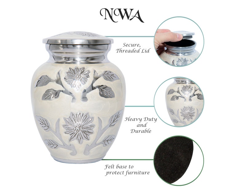 May include: White cremation urn with a silver floral design. The urn has a secure threaded lid and a felt base to protect furniture. "NWA" is printed on the top of the image.