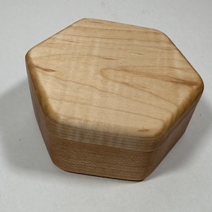 Könnte beinhalten: Eine sechseckige Holzkiste aus hellem Holz mit glatter Oberfläche.