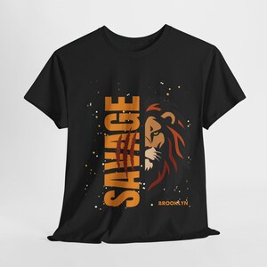 May include: Black t-shirt with an orange graphic of a lion's face and the word "SAVAGE" with claw marks. The text "BROOKLYN" is printed in orange at the bottom.
