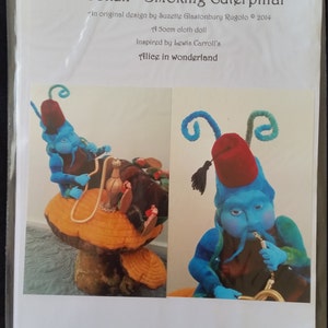 May include: A blue and red felt caterpillar smoking a hookah, sitting on a mushroom. The caterpillar is wearing a red fez and has a long, curly tail. The image is titled "Hookah - Smoking Caterpillar" and includes the text "An original design by Suzette Glastonbury Rugolo © 2014", "50cm cloth doll", "Inspired by Lewis Carroll's", and "Alice in wonderland".
