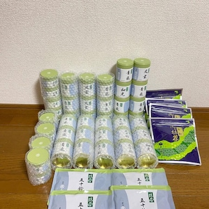 May include: A collection of cylindrical green tea tins wrapped in bubble wrap, alongside several rectangular pouches with white and green labels featuring Japanese text, including the brand name Marukyu Koyamaen and 40g net weight.