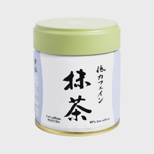 May include: A cylindrical metal tea canister with a light green lid and a white label. The label features black Japanese calligraphy, the text "Low caffeine MATCHA", and "80% less caffeine" printed in black on a light blue background.