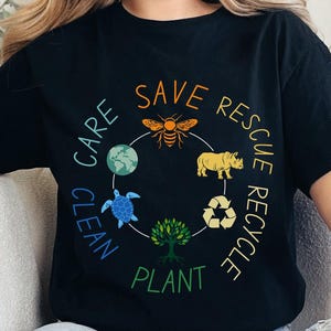 May include: Black t-shirt with a circular graphic featuring a bee, rhino, turtle, and tree, with the words "Save, Rescue, Recycle, Care, Clean, Plant." The design is in shades of orange, yellow, green, and blue.