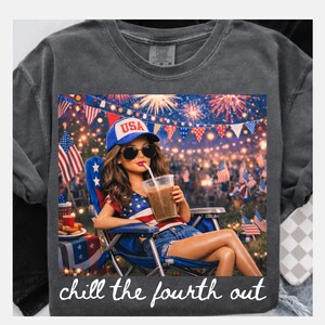 May include: Dark gray t-shirt with a graphic of a person wearing sunglasses and a USA hat, drinking a beverage. The graphic includes fireworks, flags, and the text "chill the fourth out."