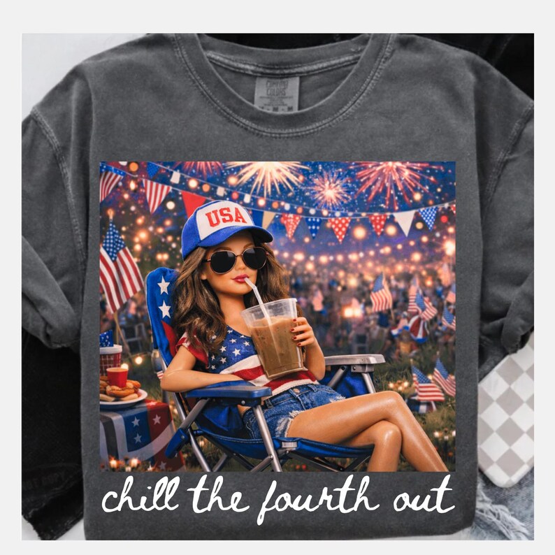 May include: Dark gray t-shirt with a graphic of a person wearing sunglasses and a USA hat, drinking a beverage. The graphic includes fireworks, flags, and the text "chill the fourth out."