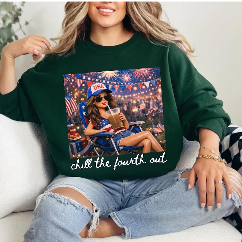 May include: Dark green sweatshirt featuring a graphic of a woman relaxing with a drink, wearing a USA hat and sunglasses, with fireworks in the background. The text "chill the fourth out" is below the graphic.