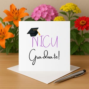 Puede incluir: Una tarjeta blanca con el texto "NICU Graduate!" en púrpura y negro, coronada con una ilustración de un birrete. La tarjeta descansa sobre un sobre blanco, con un bolígrafo plateado cerca. El fondo presenta lirios naranjas, hortensias rosas, flores amarillas y una zinnia roja.