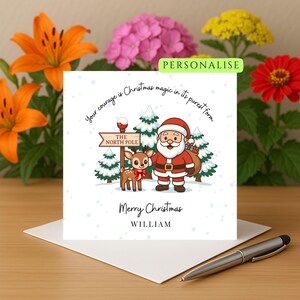 Puede incluir: Tarjeta de Navidad con una ilustración de Papá Noel, un reno y un letrero que indica el Polo Norte. La tarjeta incluye el texto "Your courage is Christmas magic in its purest form" y "Merry Christmas WILLIAM".