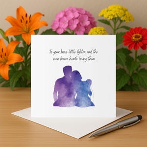 Puede incluir: Tarjeta de felicitación blanca con una ilustración en acuarela de dos figuras abrazándose, en tonos morados y azules. La tarjeta incluye el texto: "To your brave little fighter, and the even braver hearts loving them."