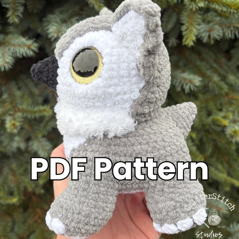Puede incluir: Un b&uacute;ho de peluche de ganchillo gris y blanco con grandes ojos amarillos y negros. El texto "PDF Pattern" se muestra en la parte delantera. El peluche tiene una textura esponjosa.