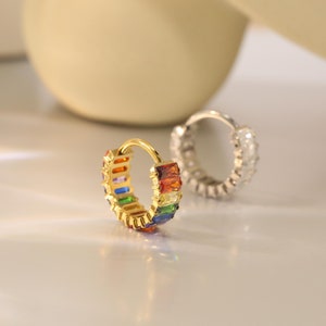 May include: A gold hoop earring with a rainbow of colorful rectangular stones.